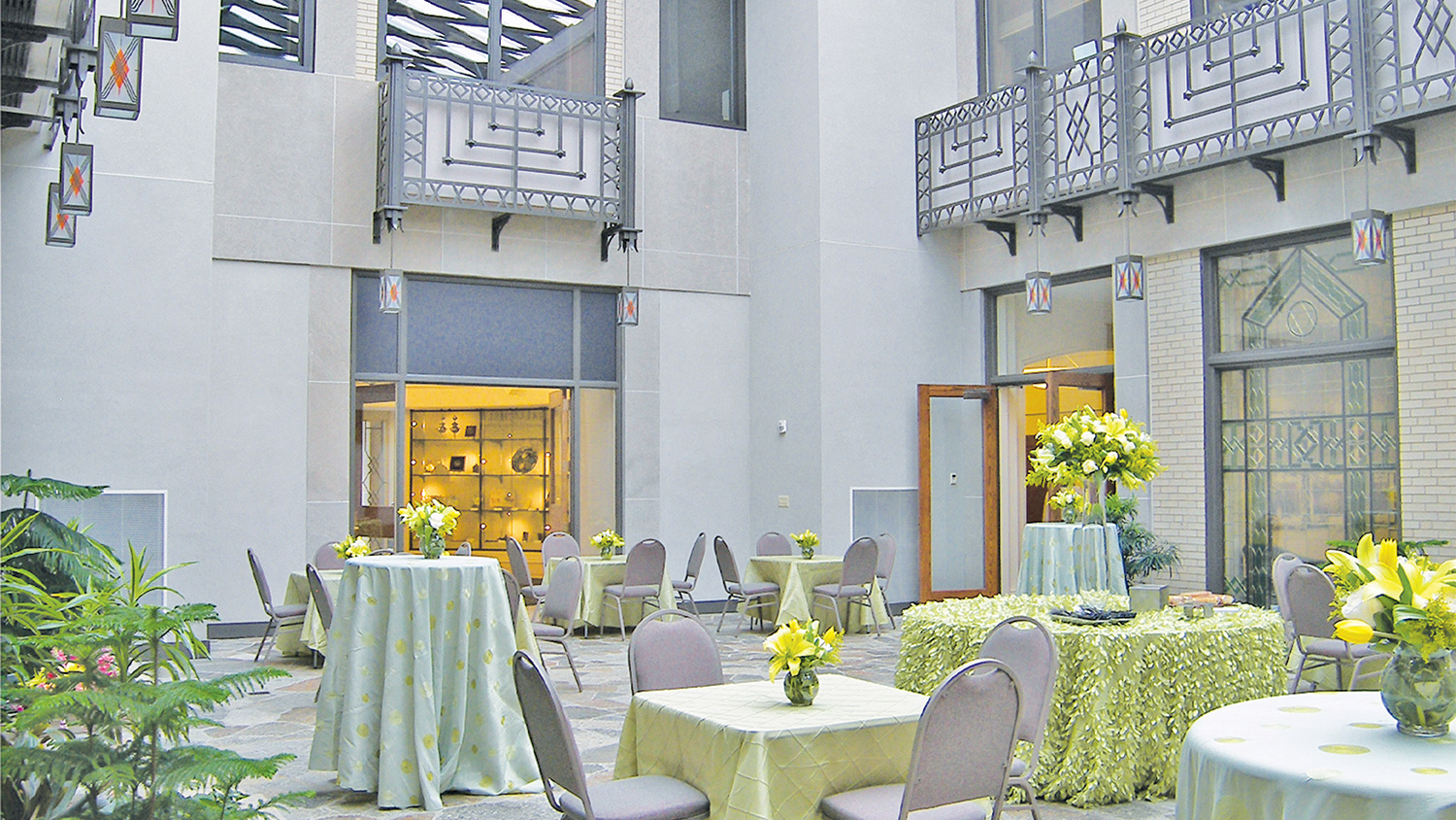 Aaron Court atrium set for a reception, featuring cocktail tables, floral arrangements, and natural light in an elegant indoor gathering space.