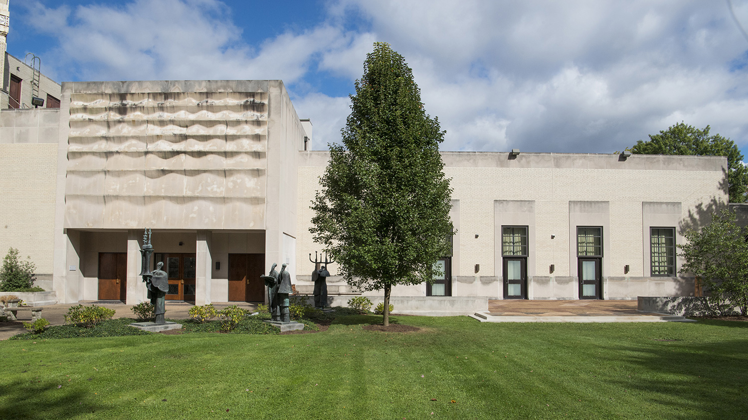 Outdoor terrace and garden area adjacent to the synagogue building, featuring sculptures, landscaped grounds, and open gathering space.