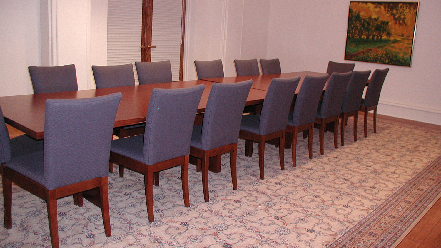 Conference room with a large meeting table and upholstered chairs, designed for board meetings, presentations, and small group gatherings.