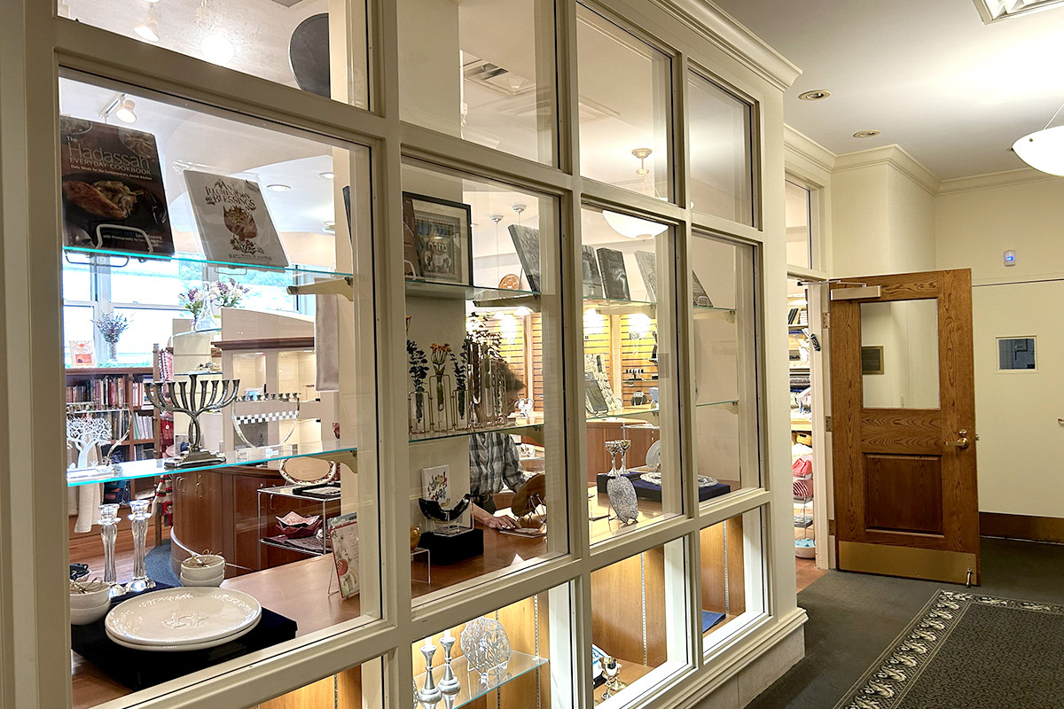Gift shop display featuring Judaica, books, and decorative items viewed through glass display windows.