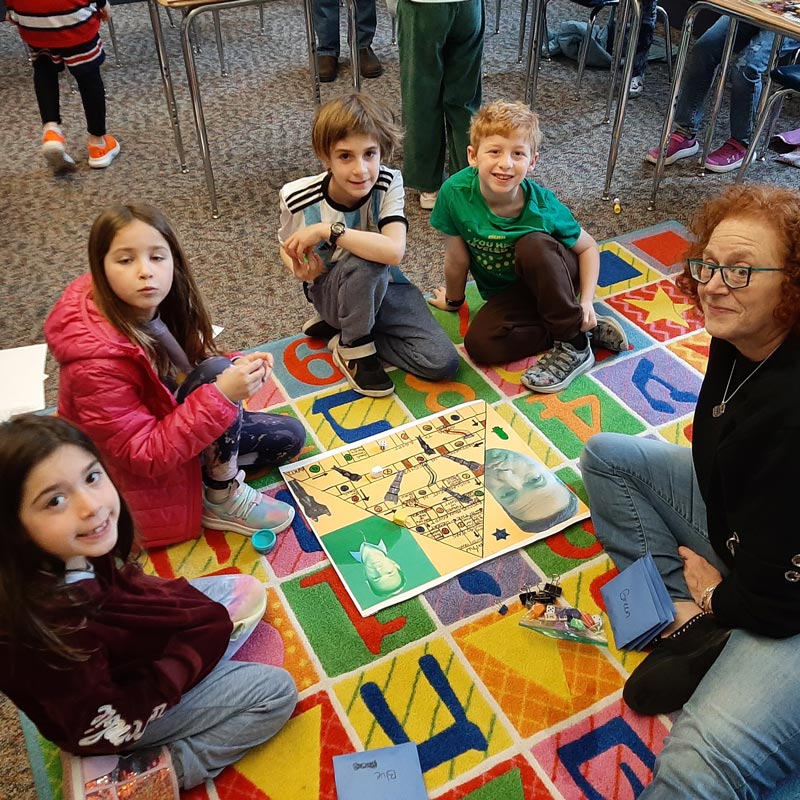 Religious school students gather with a teacher for a small-group educational activity on a classroom rug.