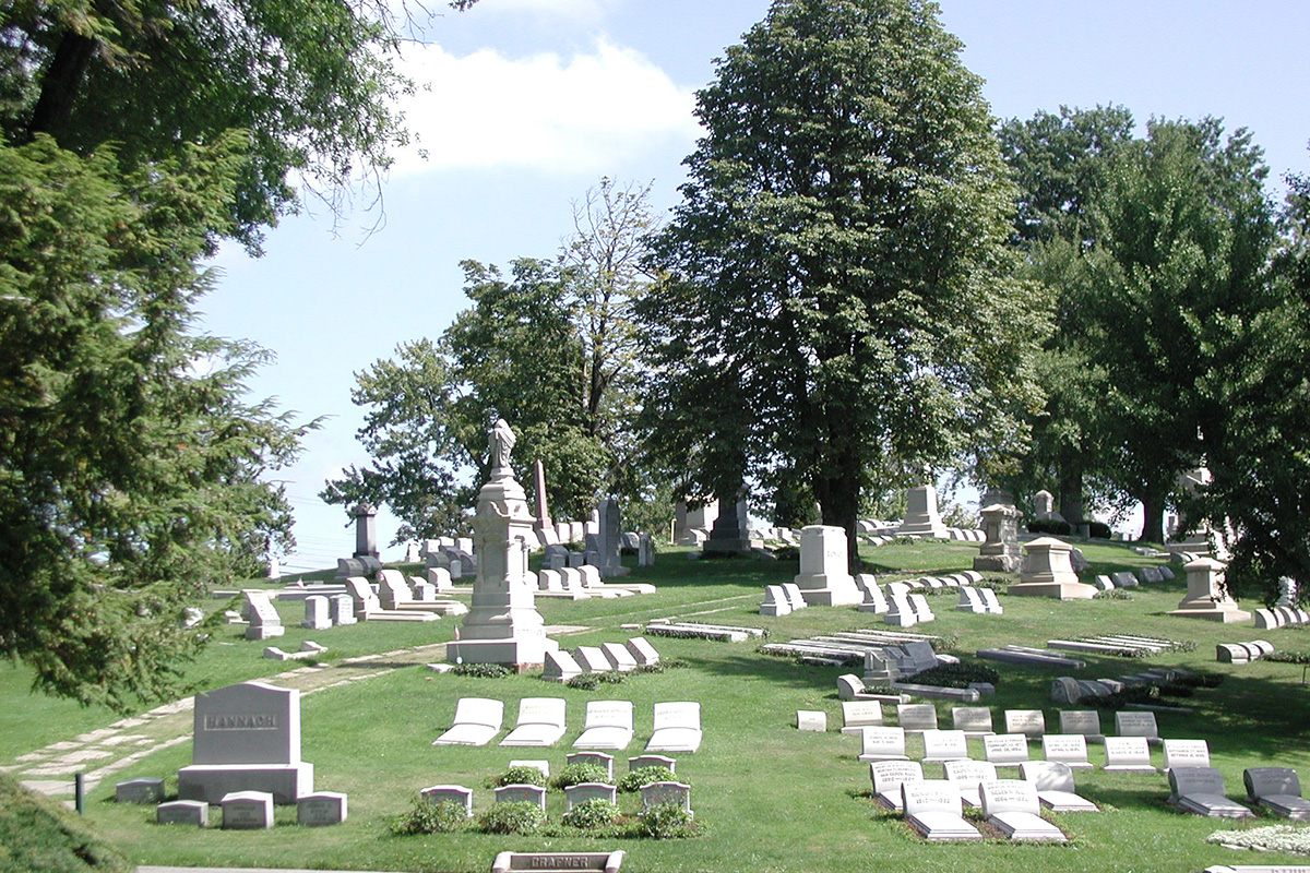 West View Cemetery with traditional upright headstones and monuments set among rolling green lawns and mature shade trees.