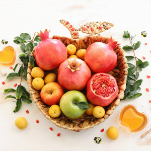 heart shaped basket with apples, pomegranates and honey